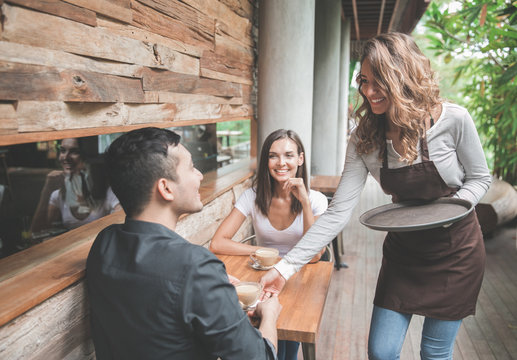 Waitress Serving Coffee To Couple Customer