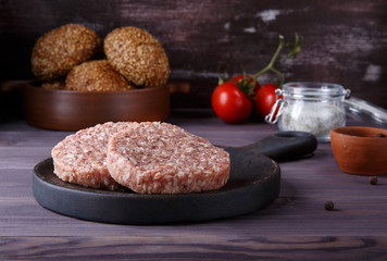 Raw minced beef meat burger cutlets on dark wooden background.