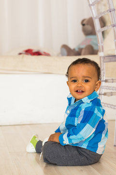 Full length portrait of a young mixed race boy sitting on the floor.