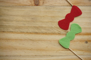 Top or flat lay view of Photo booth props a red bow tie and a green bow tie on a wooden background flat lay. Birthday parties and weddings.