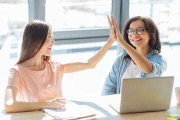 Delighted positive students giving high five
