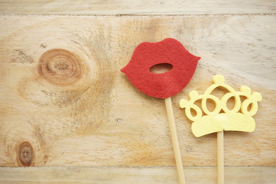 Top or flat lay view of Photo booth props a red lips and a yellow crown on a wooden background flat lay. Birthday parties and weddings.