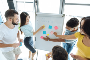 Delighted positive people putting sticky notes to the whiteboard