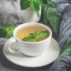 Natural mint tea and fresh mint leaves on a gray background
