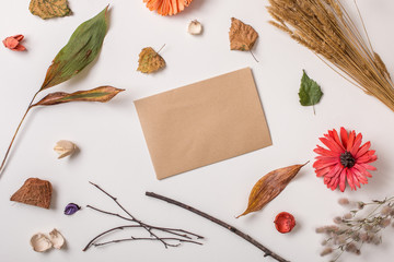 Autumn background: fallen leaves, dry petals, dried flowers and plants with craft rustic paper simple rustic branches on white. Top view. Flat lay.