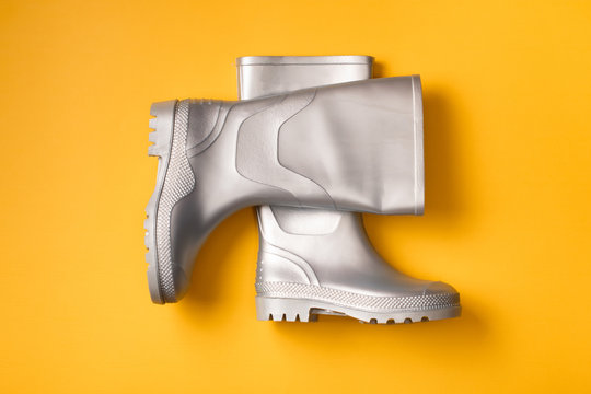 Top view of trendy silver rain boots on orange background.