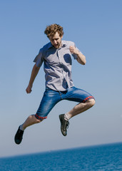 Obraz premium Carefree man jumping by sea ocean.