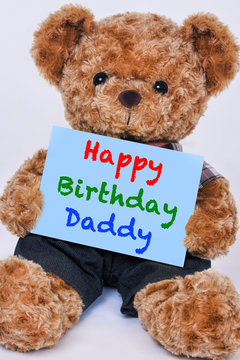 Teddy bear holding  blue sign saying Happy Birthday Daddy