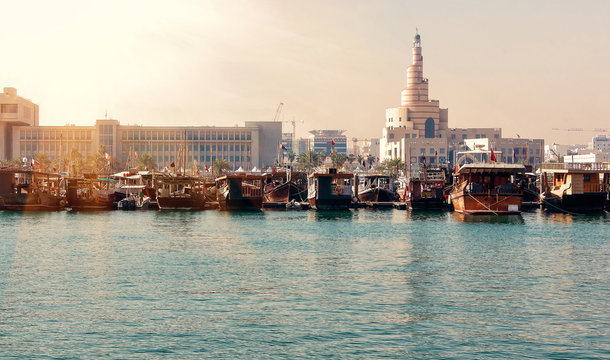 View of embankment with numerous traditional wooden ships in Doha, Qatar at sunrise