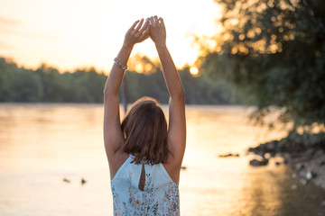 Frau streckt sich in der aufgehenden Sonne am Rhein