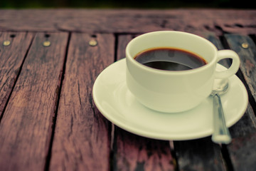 A white coffee cup on wooden table in the garden, Black coffee on wooden background, coffee break in the morning, relaxing and refreshing concepts.