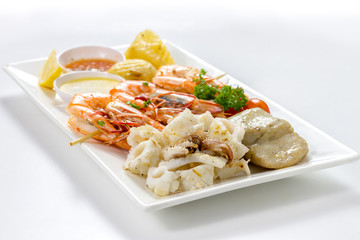 Mixed Roasted Seafood (Small Platter Set) Contain Grilled Big Shrimps, Calamari Squids and Barracuda Fish Pepper Garlic with Spicy Chili Sauce & Potatoes, Front Side View, Selective Focus at Food.