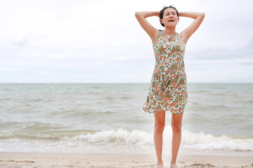 Happy Asian young woman stance and relax at the seaside on the vacations.