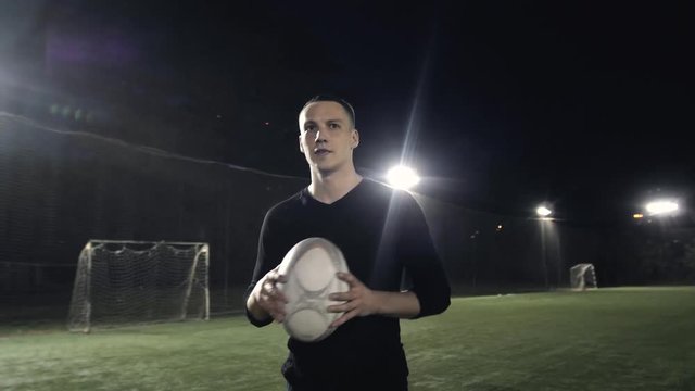 Rugby fan player in arena against rugby players training with ball, dark football arena