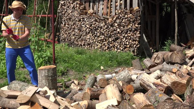 farmer man split log with axe village yard near wood pile. 4K 