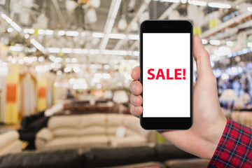 Hand with phone in the background of a furniture store. 
