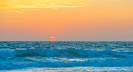 Obraz premium Sea along a sandy beach in the light of sunset in summer