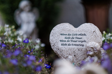 Herz aus Stein auf einem Friedhof mit dem Text 