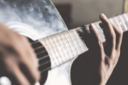 close up blurred background of hands playing guitar