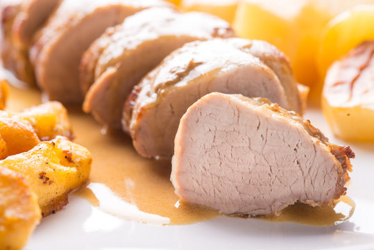 Filetto di maiale arrosto con patate e spicchi di mela arrostite servite su un piatto