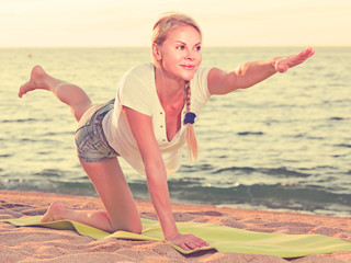 Smiling adult woman in white T-shirt is doing excercises on endurance