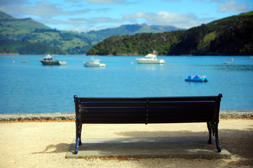 Naklejka na ściany i meble A lone bench at beach of Akaroa,NewZealand.