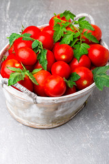 Red tomato in grey basket on grey background. Harvest.  Full box of tomatoes.