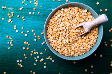 Dry yellow pea in green bowl on green background. Top view.