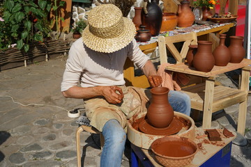 The master is making a pot. The sunny day, the street master