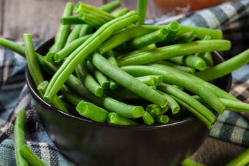 Raw green beans in a black dish