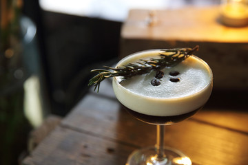 Coffee cocktail with coffee bean and rosemary on top with wood background