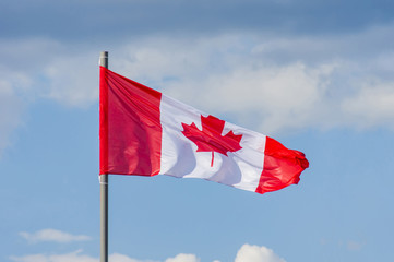 The National flag of Canada flay over the blue sky