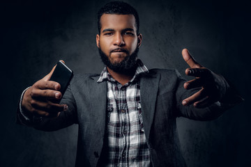 Black male dressed in a fleece shirt and a jacket using a smart phone.