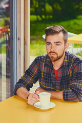 A man drinks coffee in a cafe.