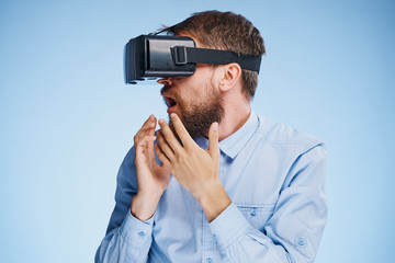 A young guy with a beard on a blue background with virtual reality glasses