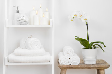 Fototapeta na wymiar Shelf with clean towels, candles, flowerpot on bathroom wooden table