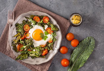 Baked egg with kale, goat cheese and tomatoes on plate top view