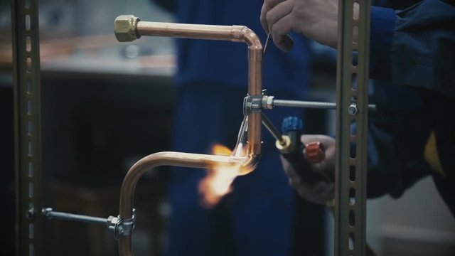 Industrial worker soldering copper pips