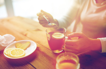 Fototapeta na wymiar close up of woman adding honey to tea with lemon