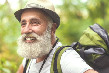 Naklejka na ściany i meble Cheerful old man admiring the nature during hiking