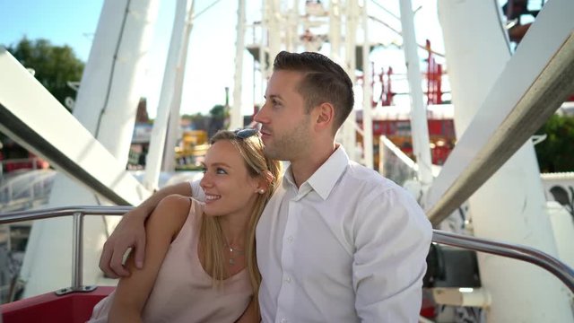 4k video happy young couple enjoying drive in ferris wheel in amusement park on sunny summer day 
