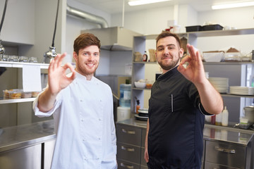 happy chefs at restaurant kitchen showing ok sign