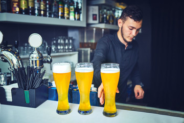 Bartender Serving Customers In Busy Bar