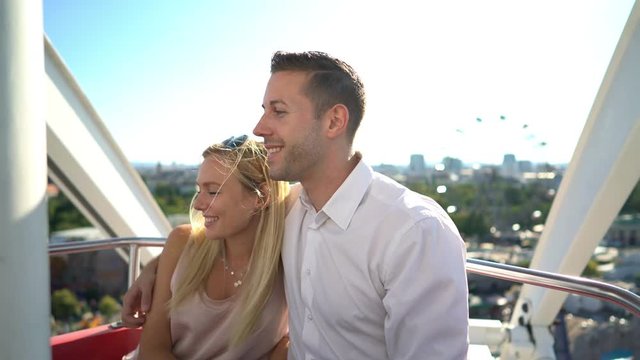 4k video beautiful 30 years old couple enjoying drive in ferris wheel in amusement park on sunny summer day with great view
