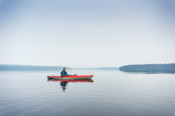 Woman in sunglasses enjoying the lake from red kayak