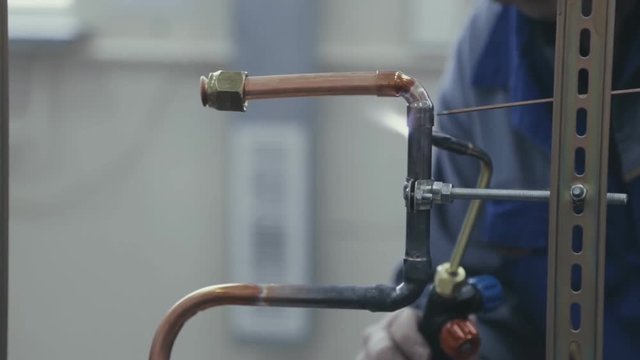 Industrial worker soldering copper pips