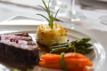Roasted meat with carrots and asparagus on a white plate