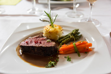 Roasted meat with carrots and asparagus on a white plate