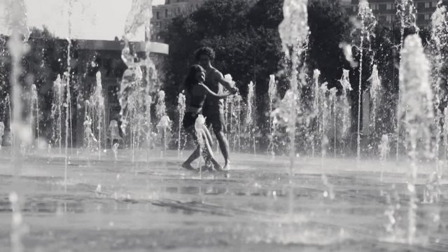 Young happy couple dancing in the fountain