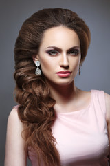Beauty portrait of a girl with an elegant bridal woven voluminous hair on long dark hair.
